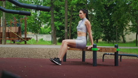 Fit-woman-do-reverse-push-ups-using-bench-in-a-Park-in-slow-motion.-Beautiful-woman-playing-sports-in-the-Park.